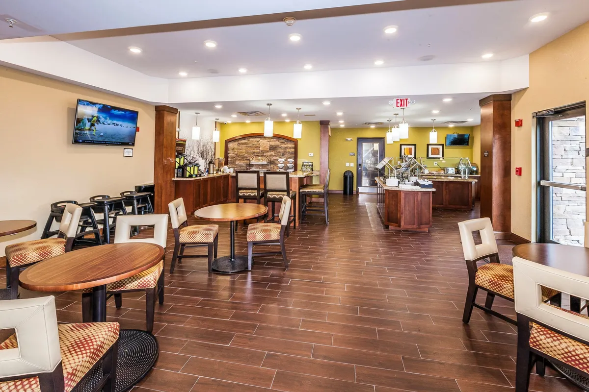 A comfortable and inviting dining area with tables, chairs, a television, and a visible food display. The setup is conducive to casual dining, socializing, and enjoying coffee or meals with family or teammates.
